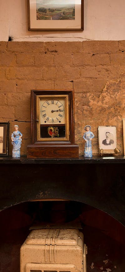 Fireplace in Mugga-Mugga cottage with historical photographs and objects
