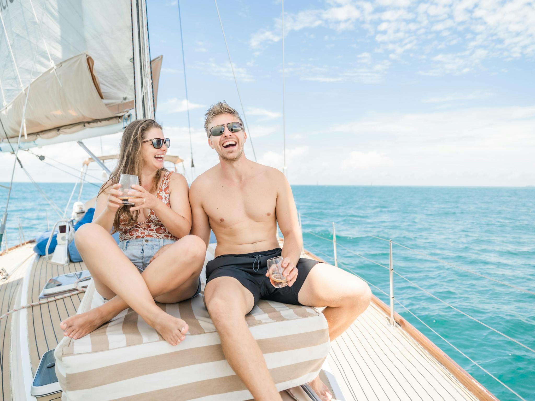 Couple on front of boat laughing as they sail along Couple on front of boat laughing as they sail along