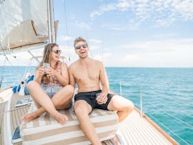Couple on front of boat laughing as they sail along