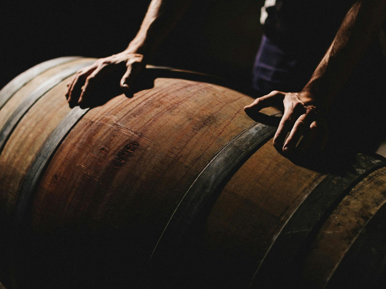 Two hands resting on a wine barrel