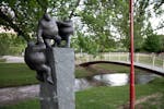 Granite sculpture with 3 figures helping each other. Situated next to a picturesque creekscape