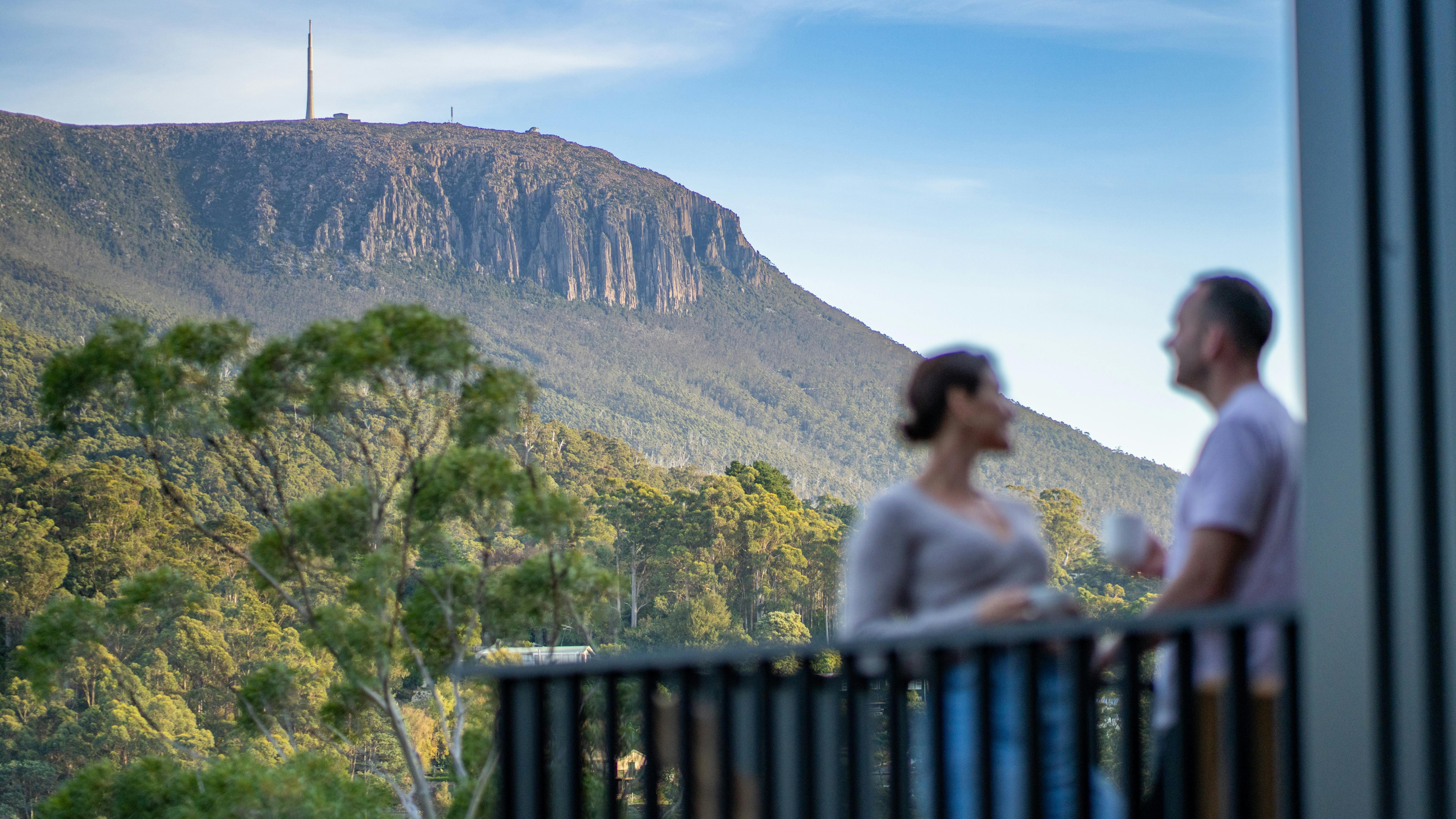 A couple out on the deck enjoying the view of kunanyi / Mt Wellington