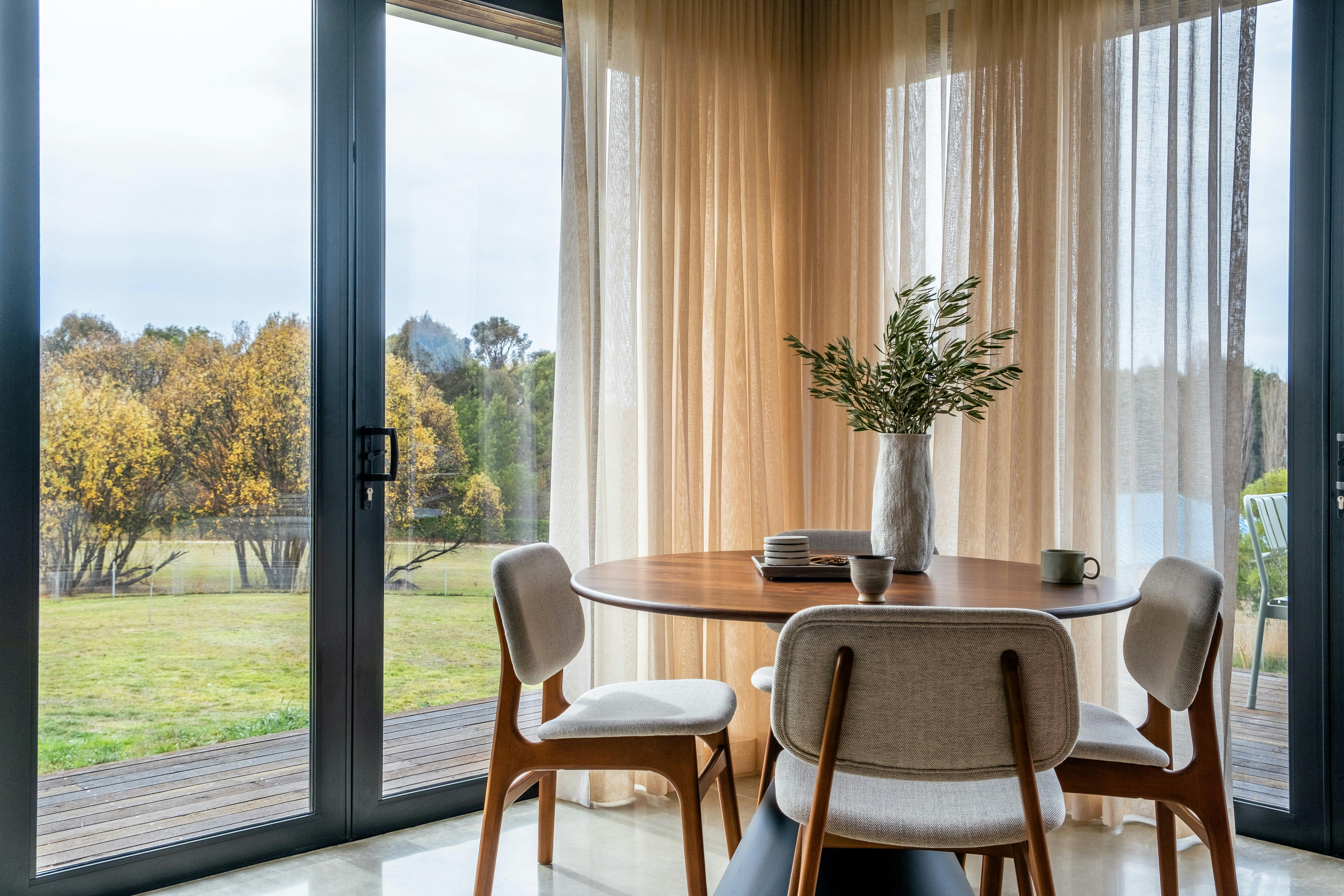 a dining room with round table and s-wave curtains