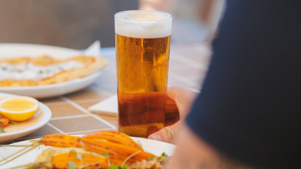Glass of cold beer on a table with pub meals including steak and seafood in a relaxed dining setting