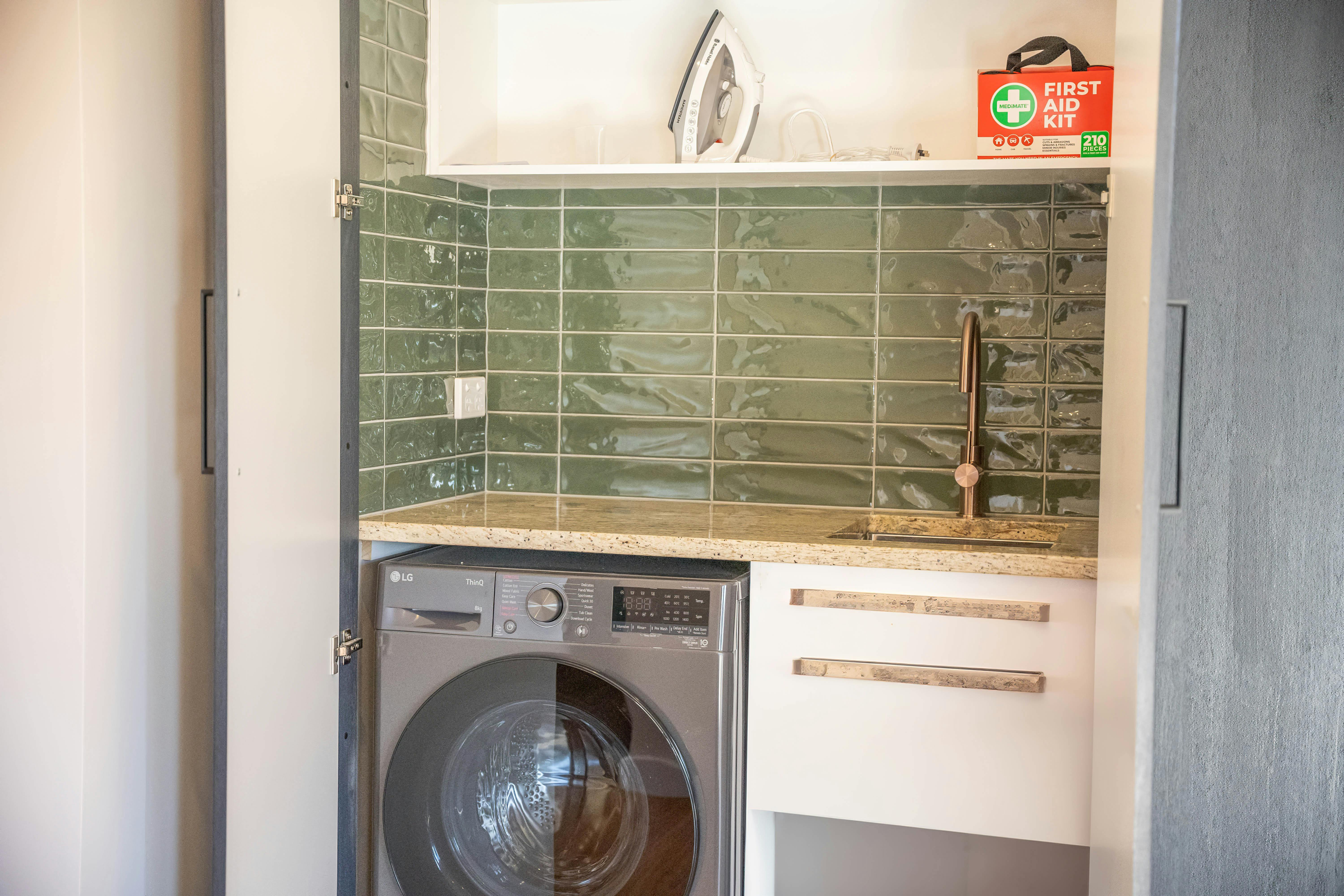 laundry area with sink, iron, washing machine, first aid kit