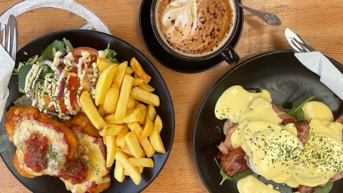 Chicken schnitzel with chips and salad, coffee and eggs Benny with bacon
