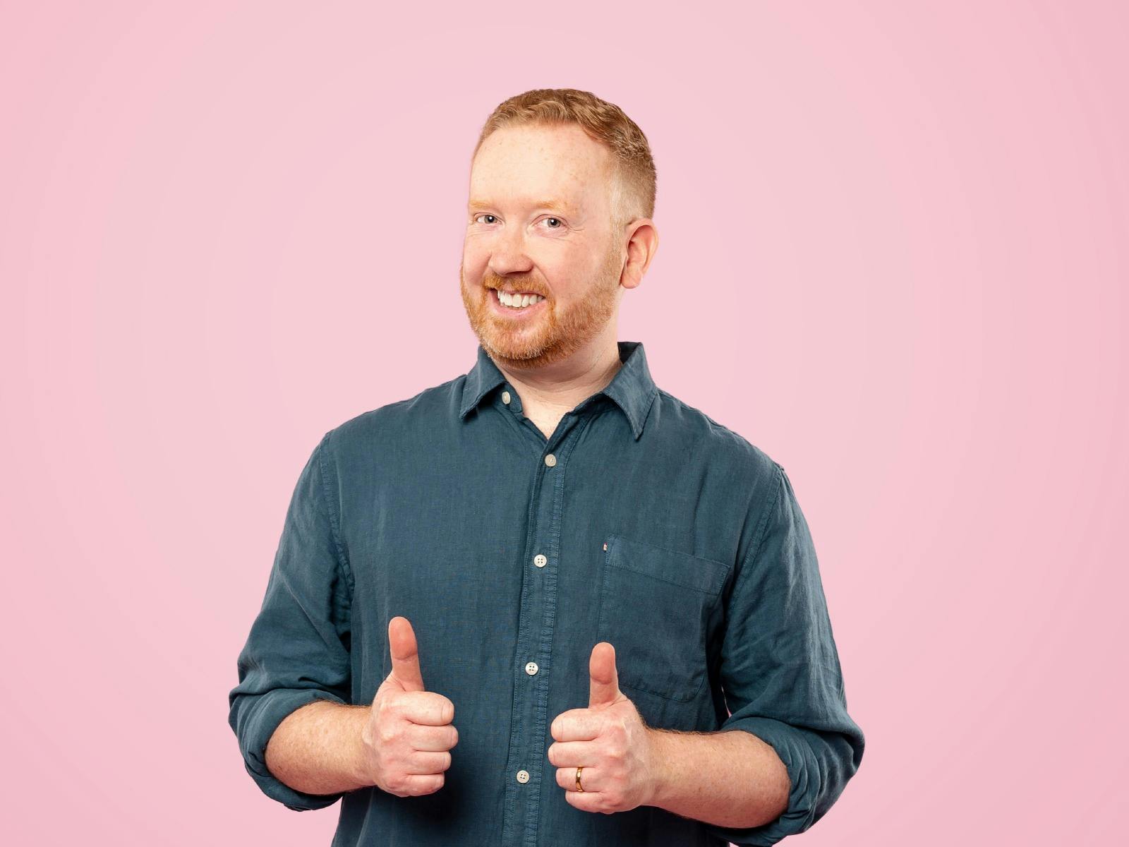 Man with red hair giving a double thumbs up and smiling