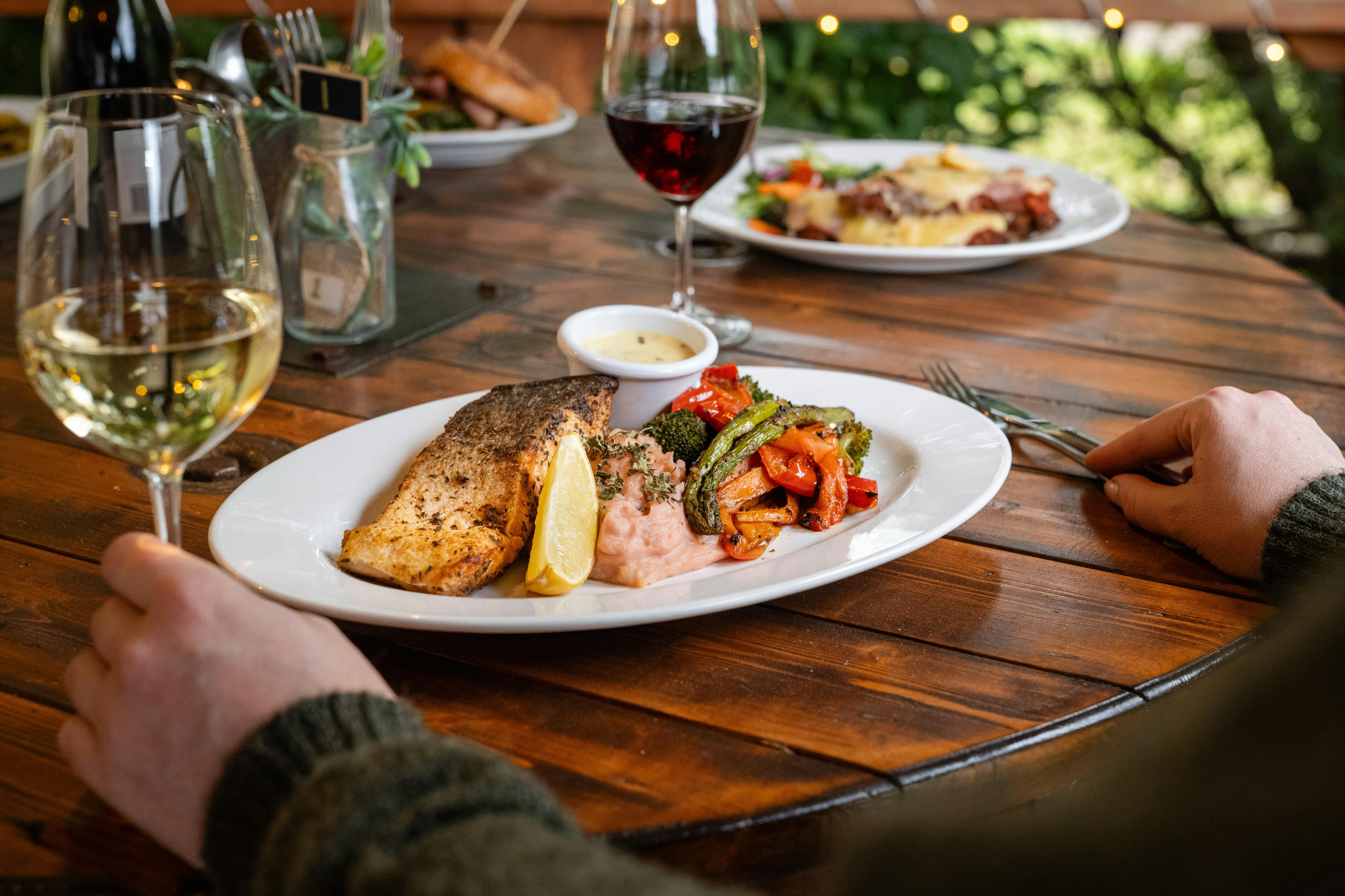 Enjoy a delectable meal of grilled salmon with roasted vegetables, perfectly paired with fine wine