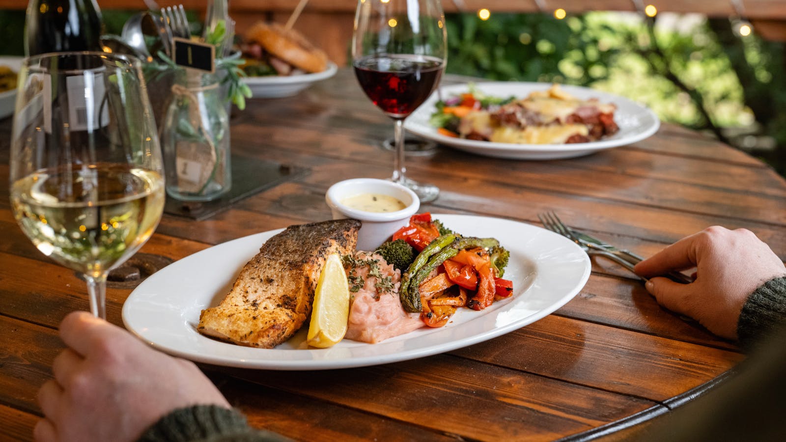 Enjoy a delectable meal of grilled salmon with roasted vegetables, perfectly paired with fine wine