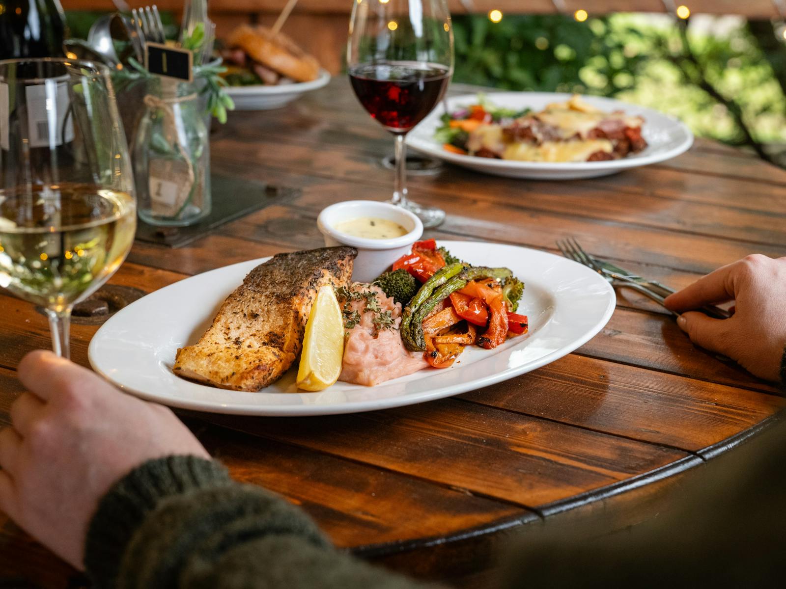 Enjoy a delectable meal of grilled salmon with roasted vegetables, perfectly paired with fine wine