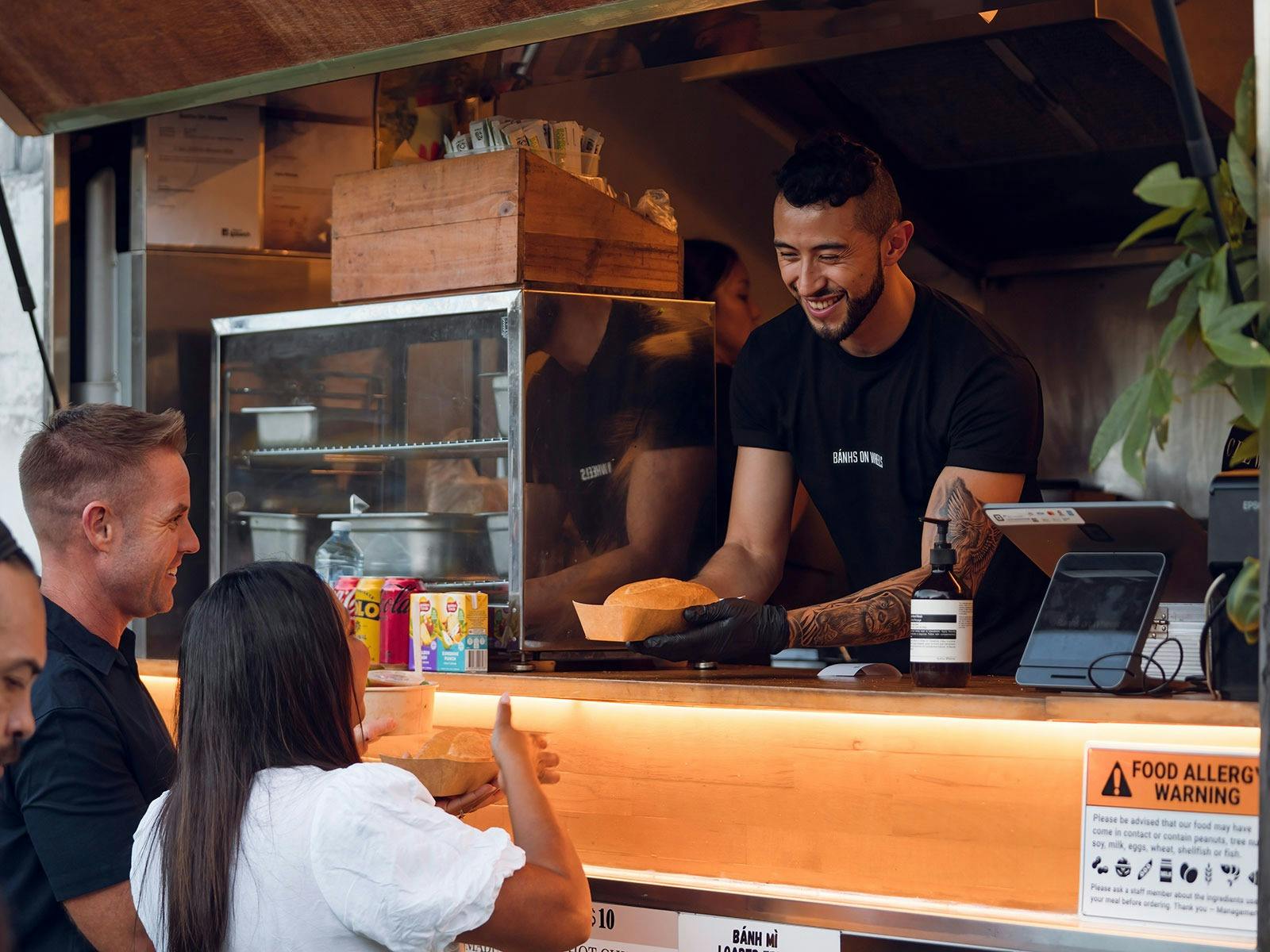 Person serving food from a food truck to a person waiting