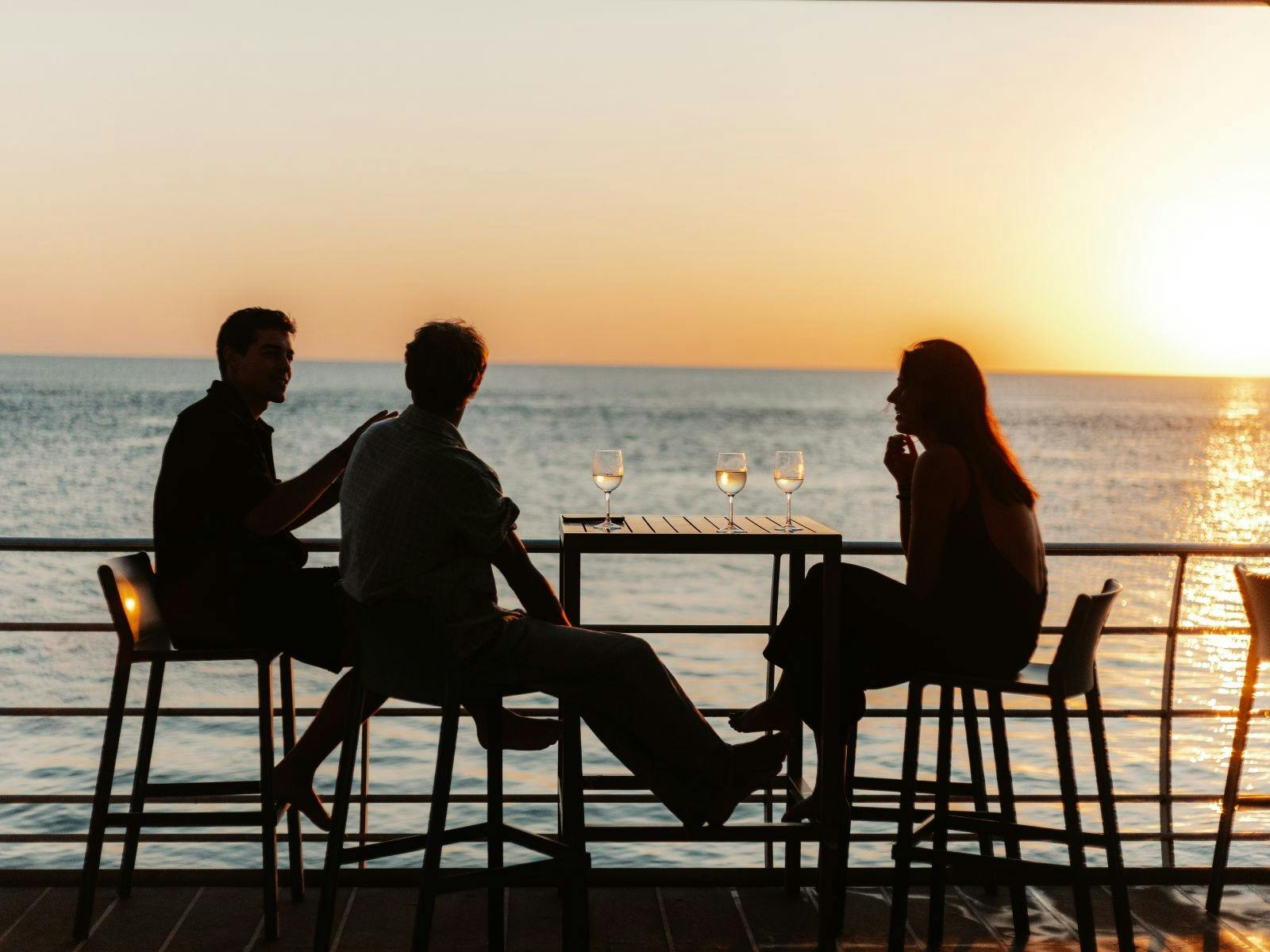 A group of people watching the sun set over the water