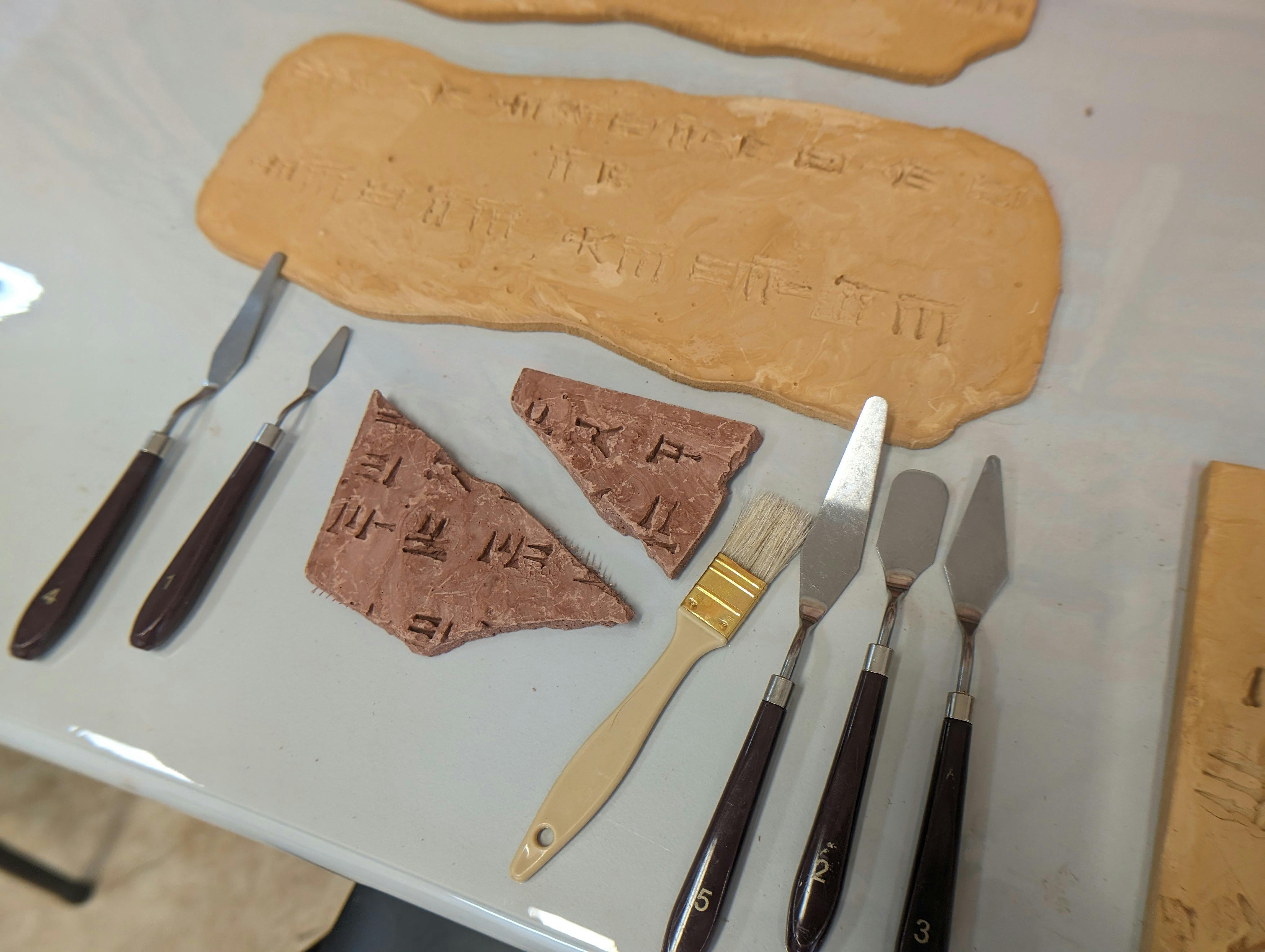A detailed view of clay tablets with cuneiform inscriptions alongside archaeological tools, creating