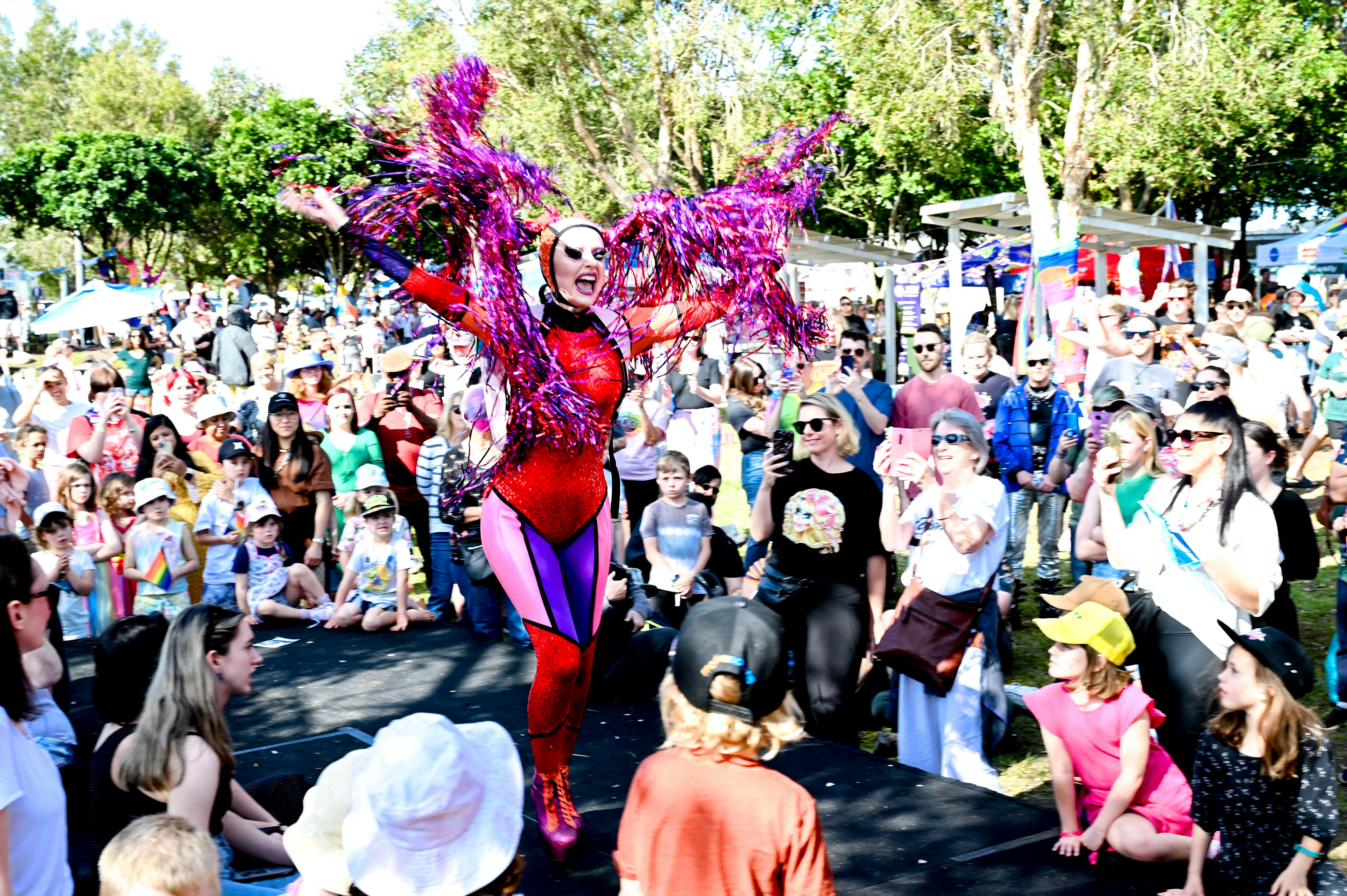A crowd of people surrounding a performer wearing a bright coloured leotard and tinsel