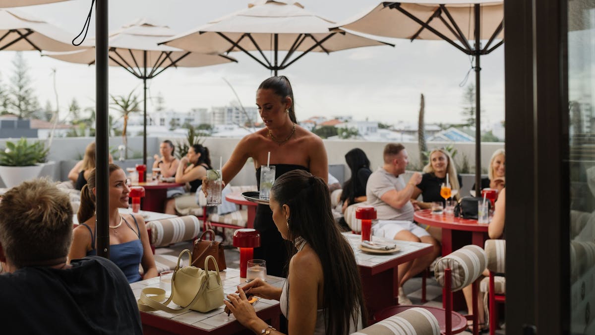 A full rooftop with people being served drinks