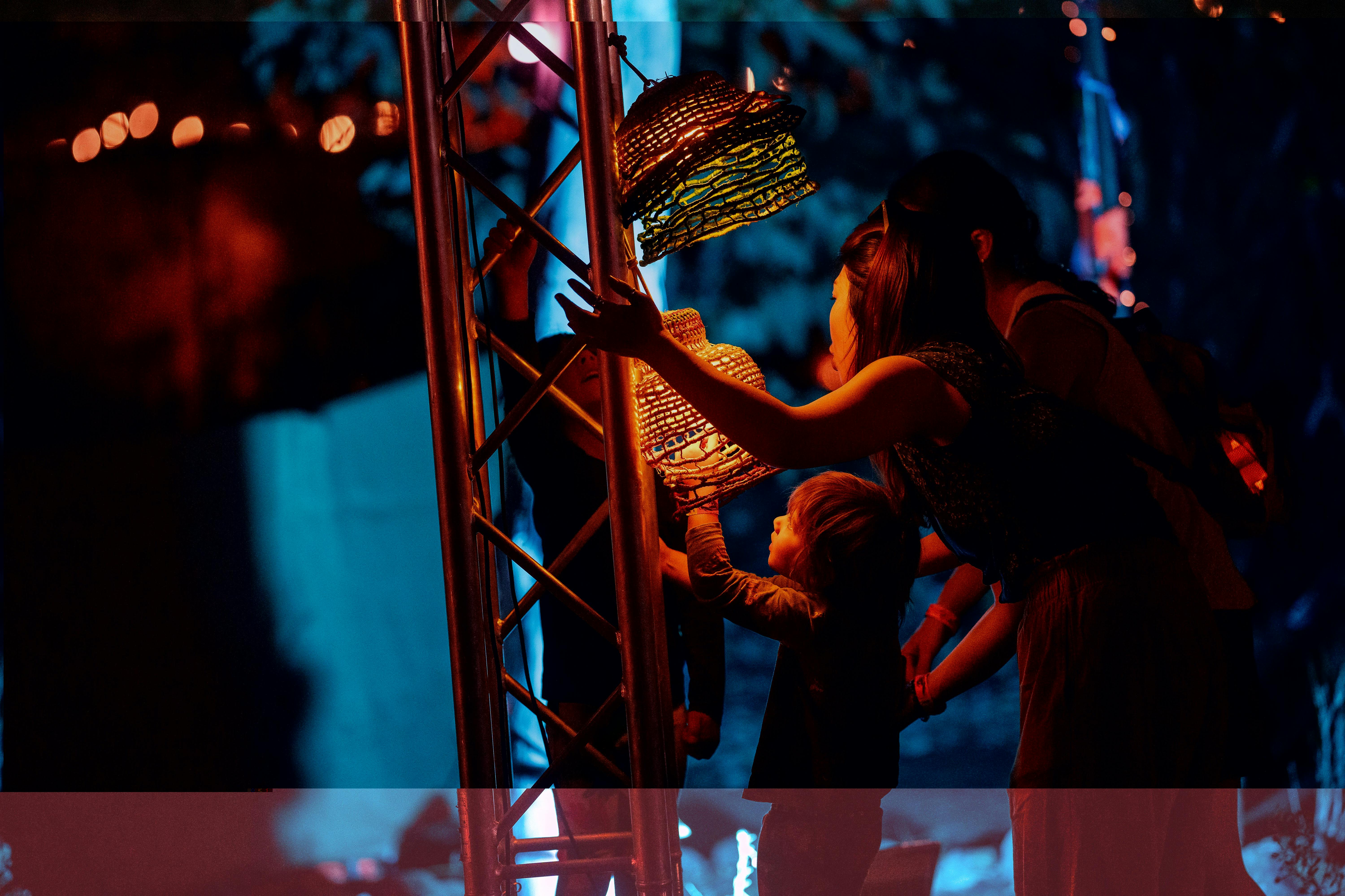 Festival-goers interact with glowing woven lanterns at Desert Festival 2023, immersed in a vibrant l