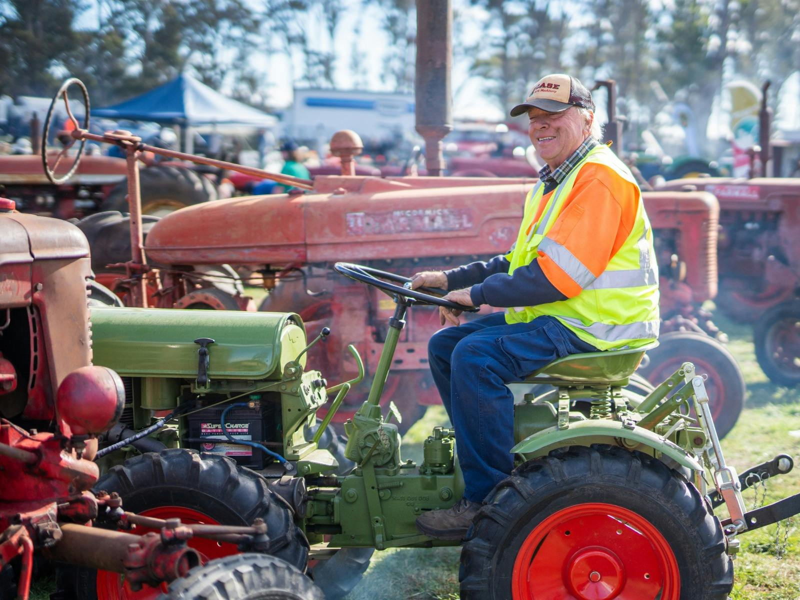 A man sits on a vintage tractor, showcasing classic machinery at Agfest.