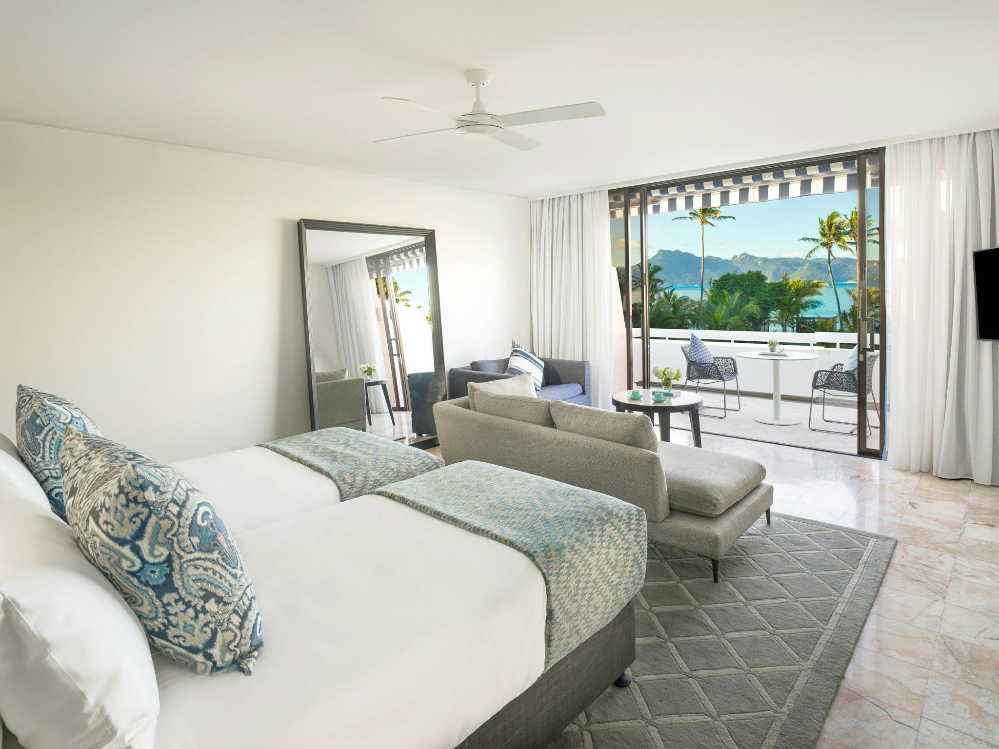 Modern twin room featuring two beds, a seating area, work desk, and a terrace overlooking the ocean. Modern twin room featuring two beds, a seating area, work desk, and a terrace overlooking the ocean.