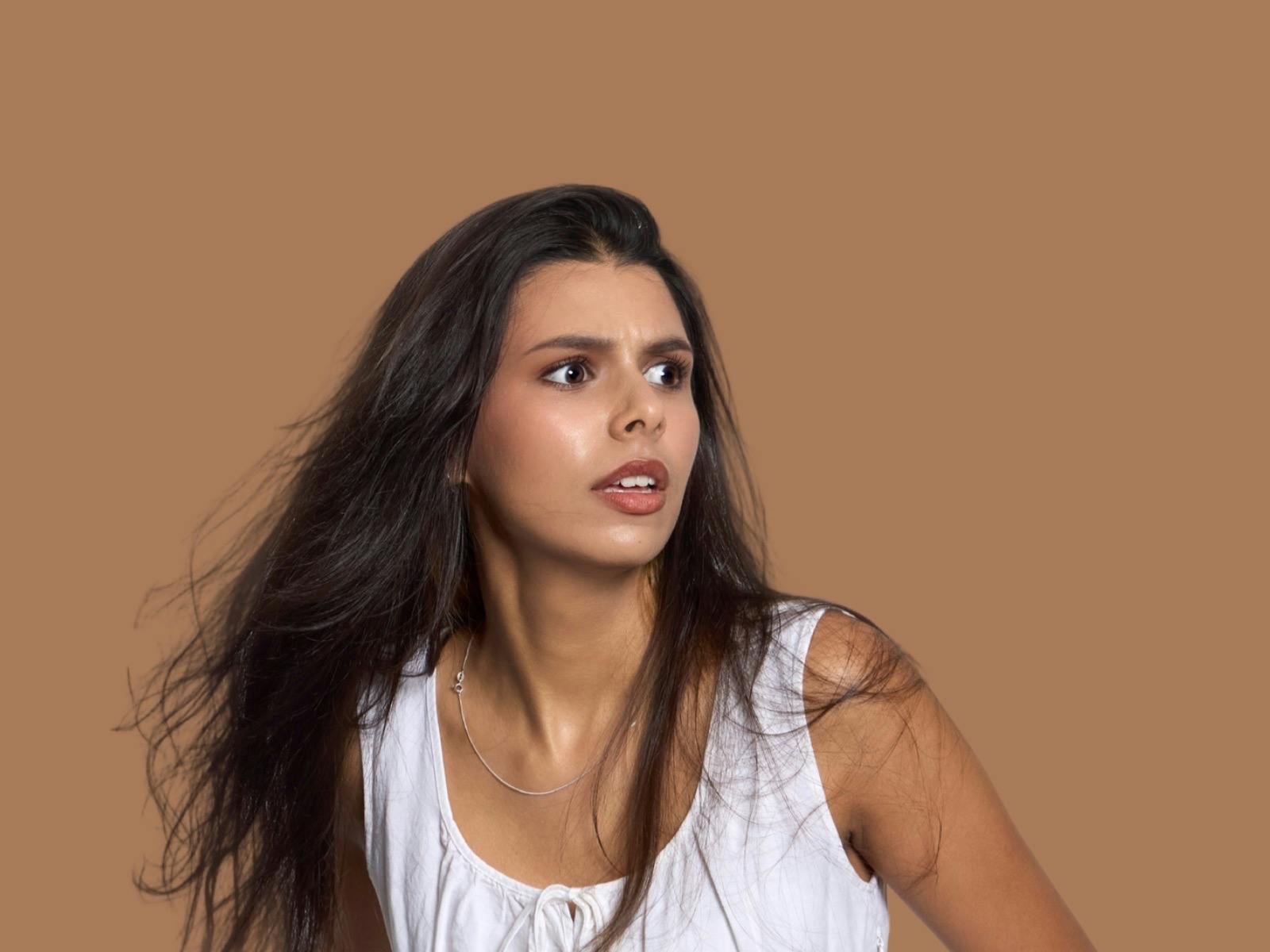 Young woman in white dress looks scared off camera