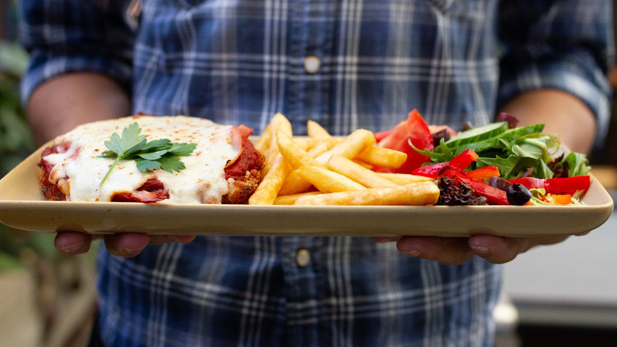 A team member holding a chicken parmy