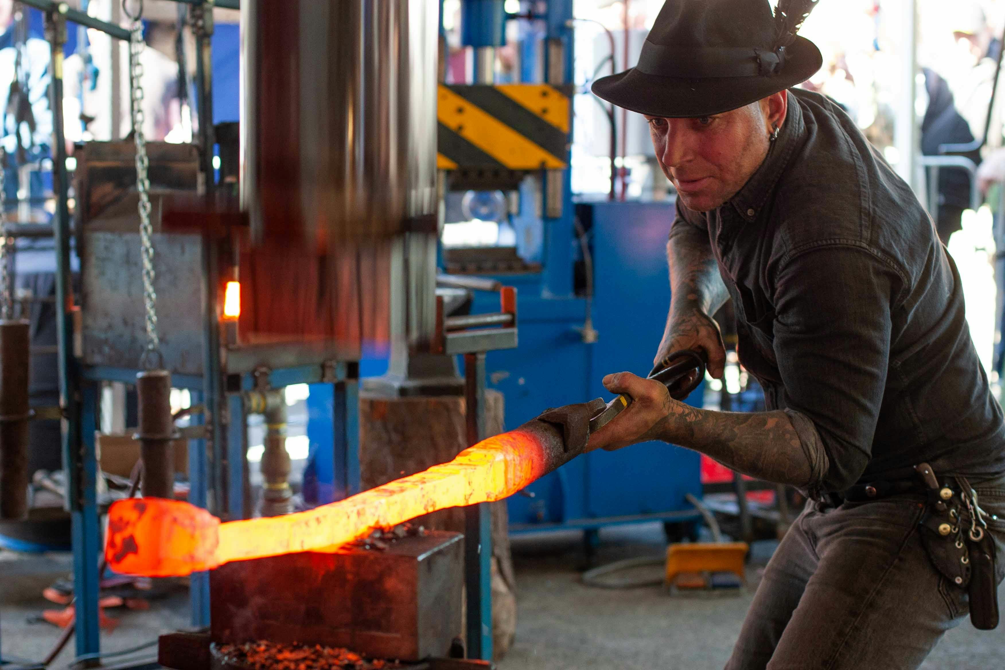 Blacksmith Pete Mattila operates a power hammer, shaping molten steel at the forge.