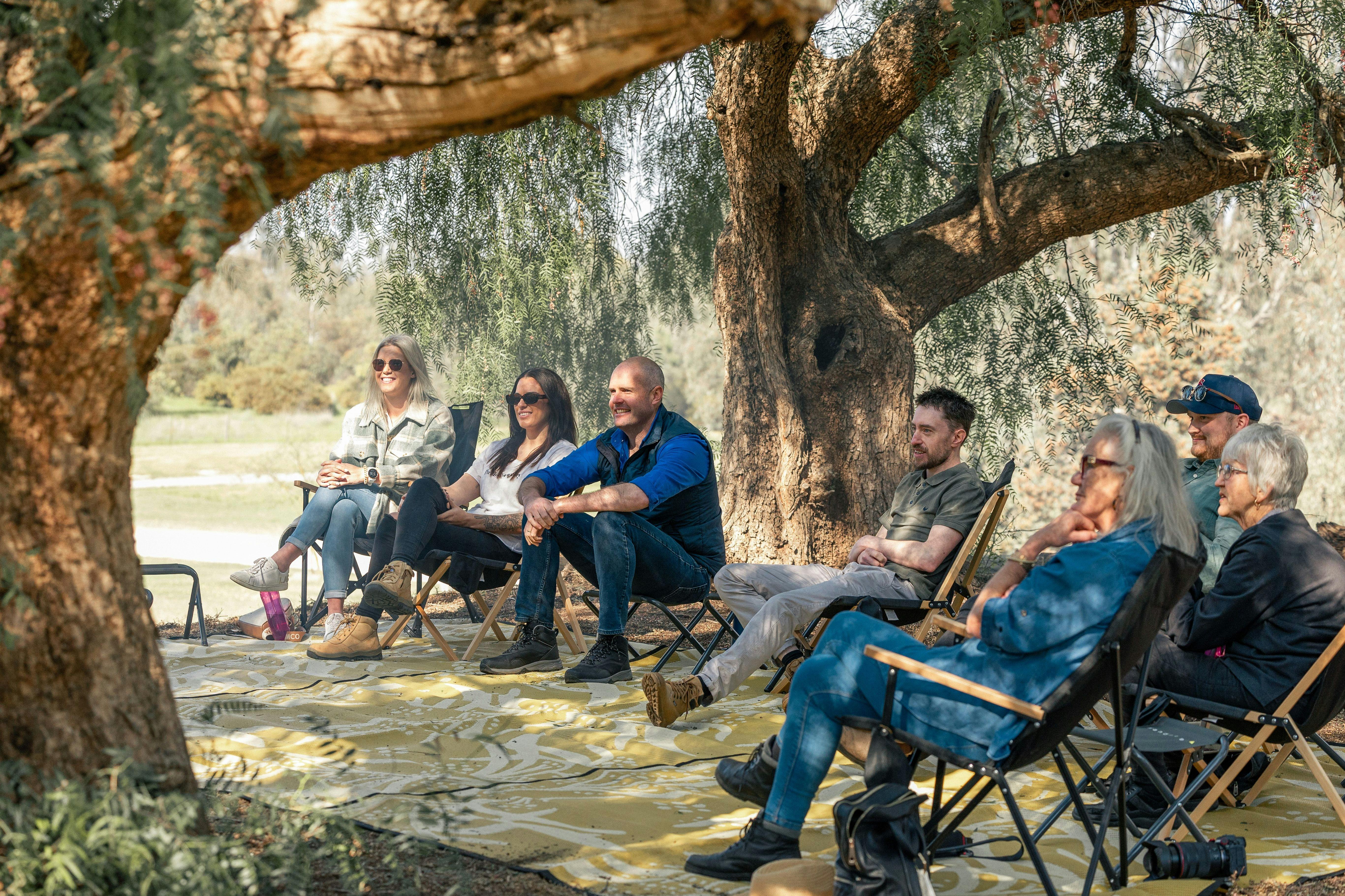 visitors sitting under peppercorn trees