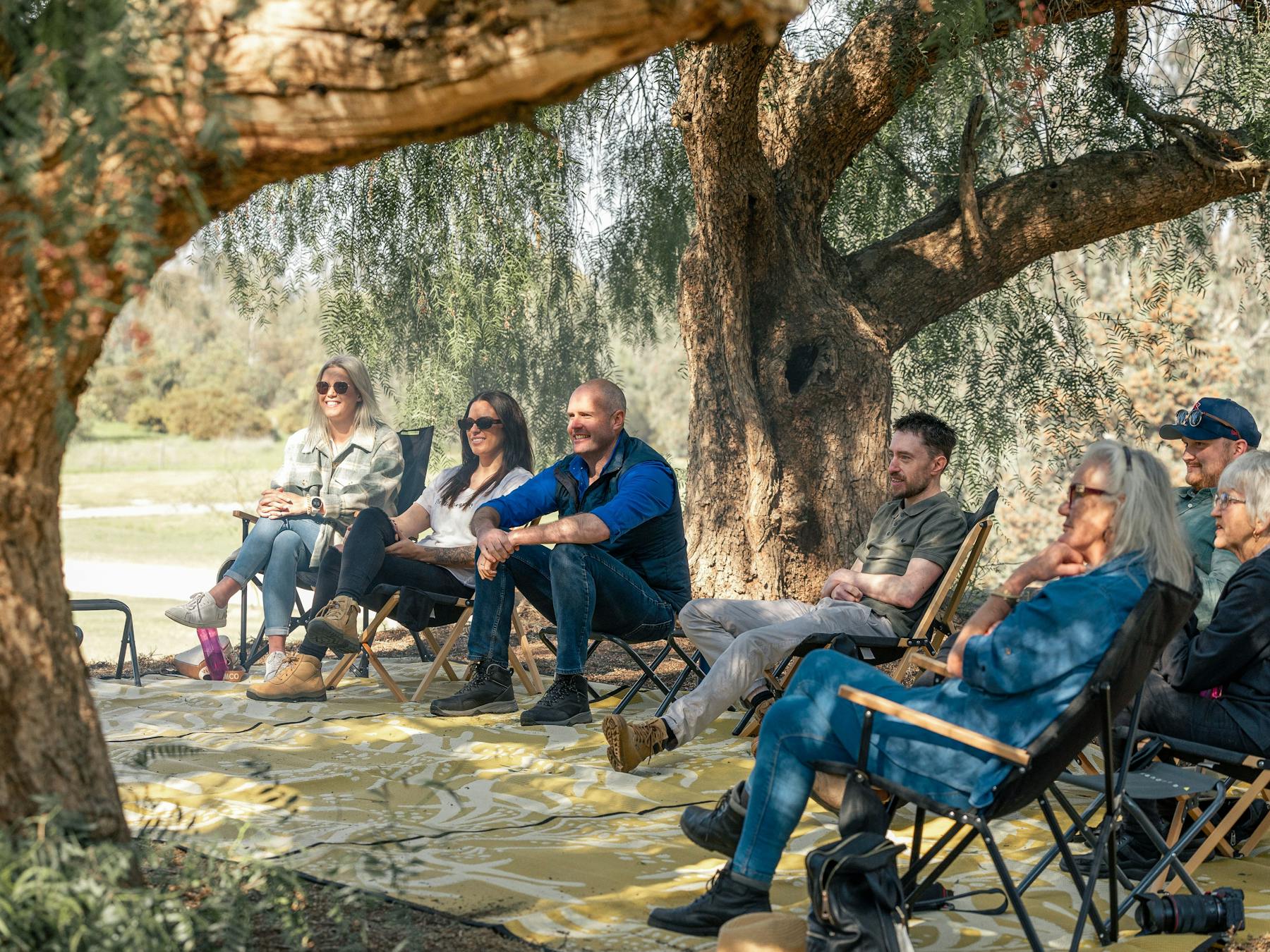 visitors sitting under peppercorn trees