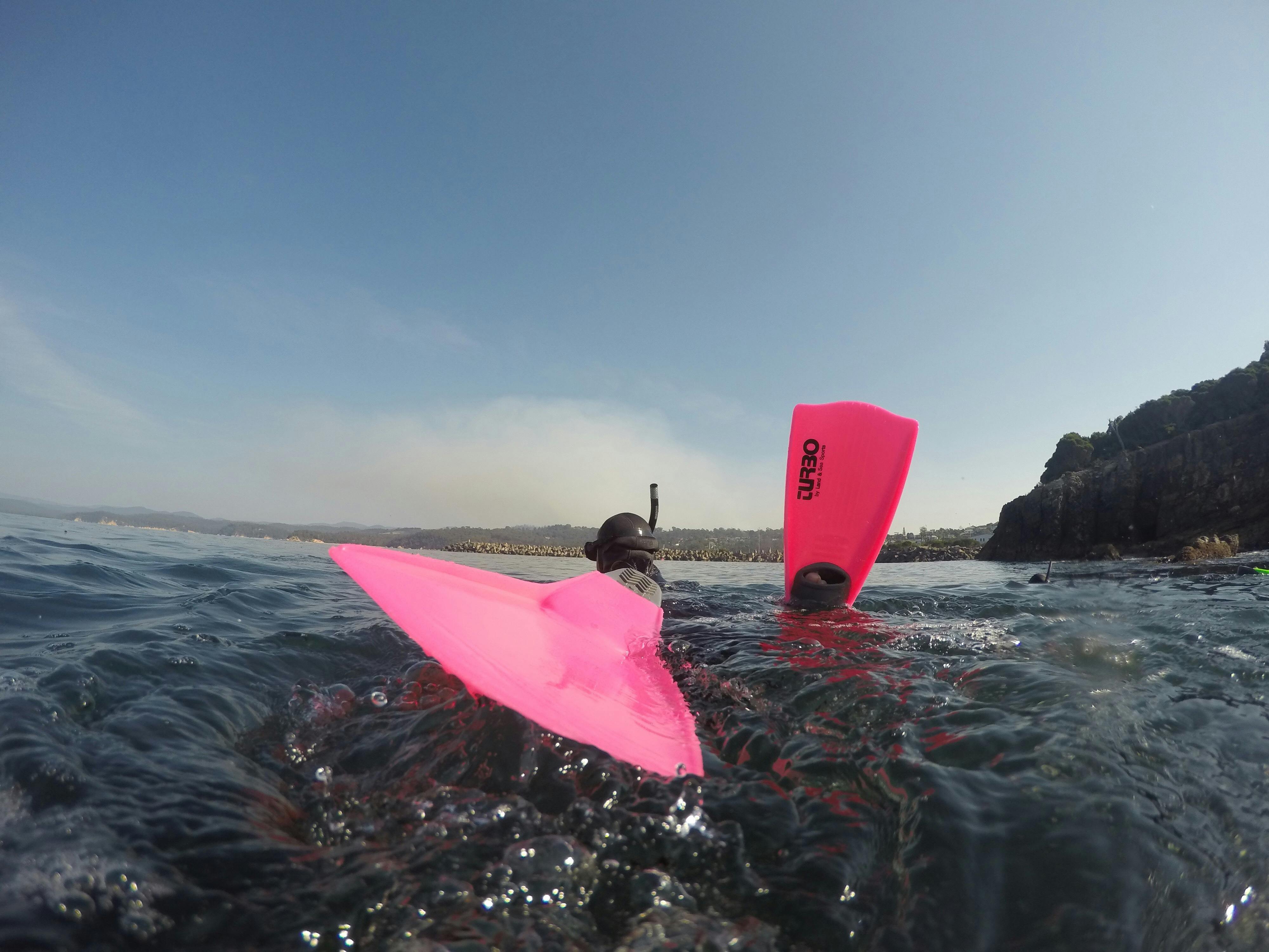 Girl wearing pink dive fins on the surface of the water