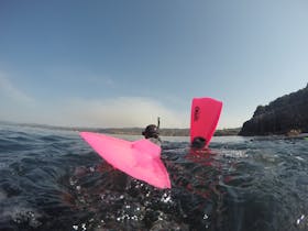 Girl wearing pink dive fins on the surface of the water