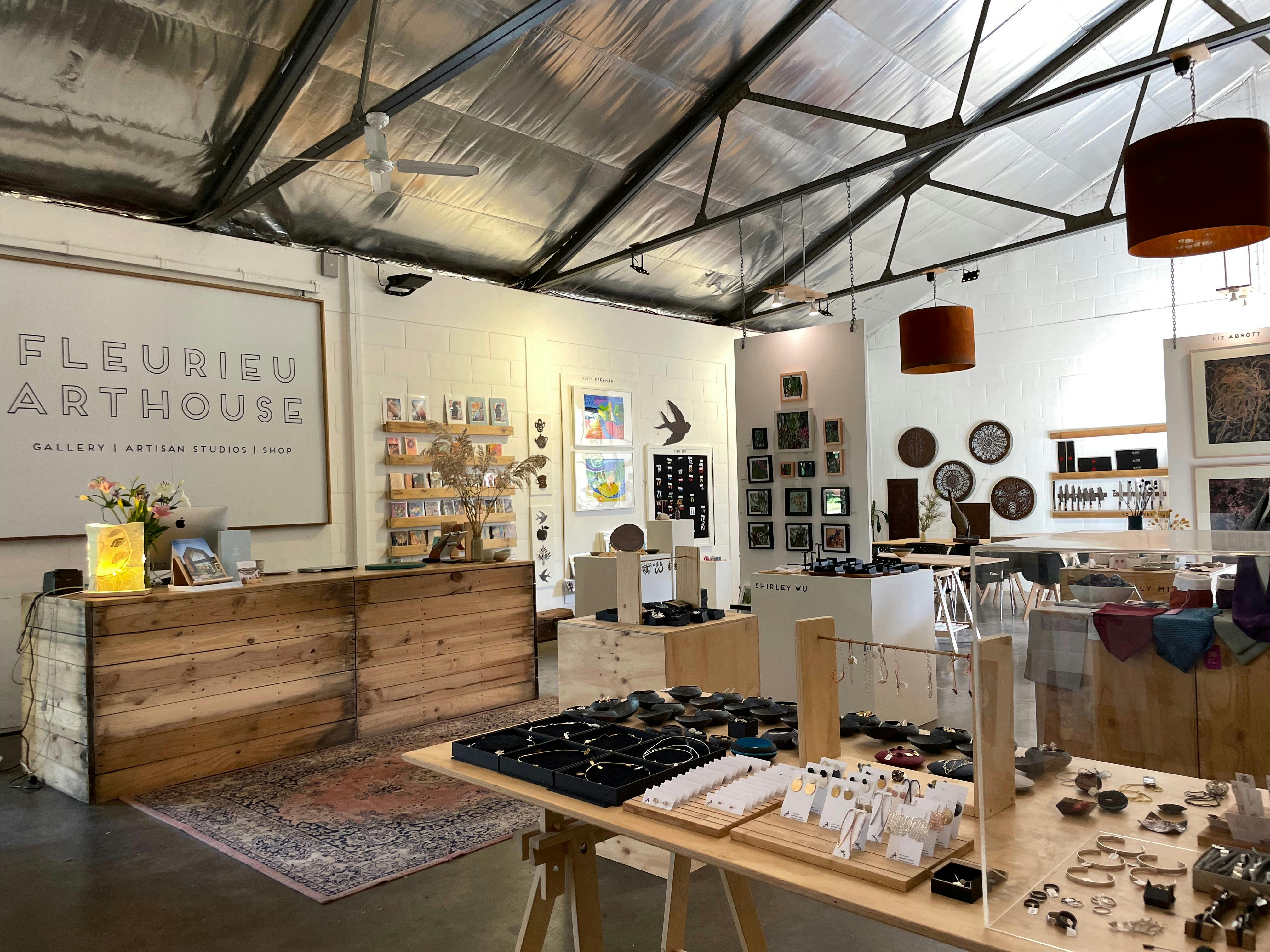 a room in a warehouse shop with a rustic counter and tables with jewellery and hanging walls