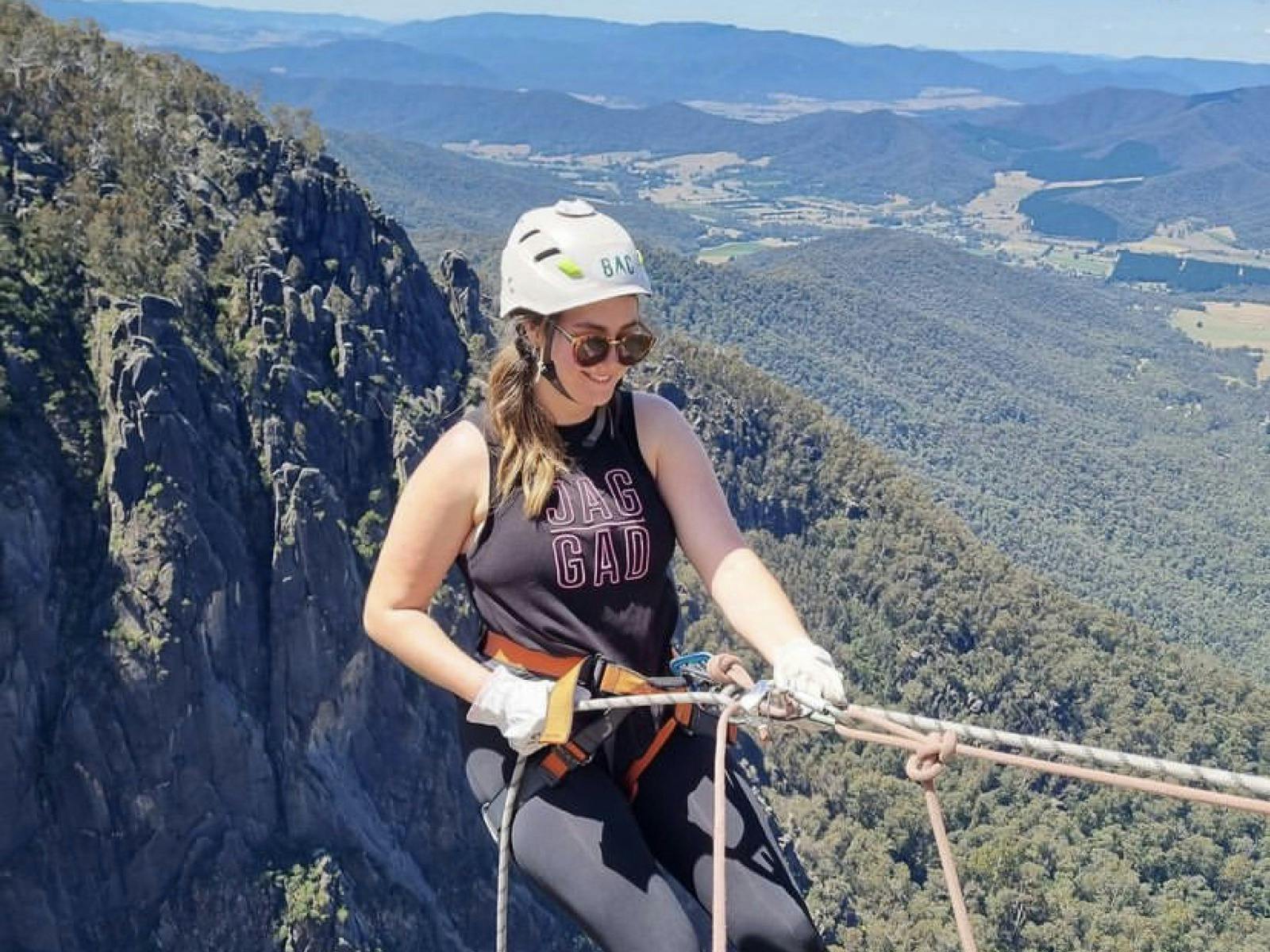 Lady abseiling with mountains behind