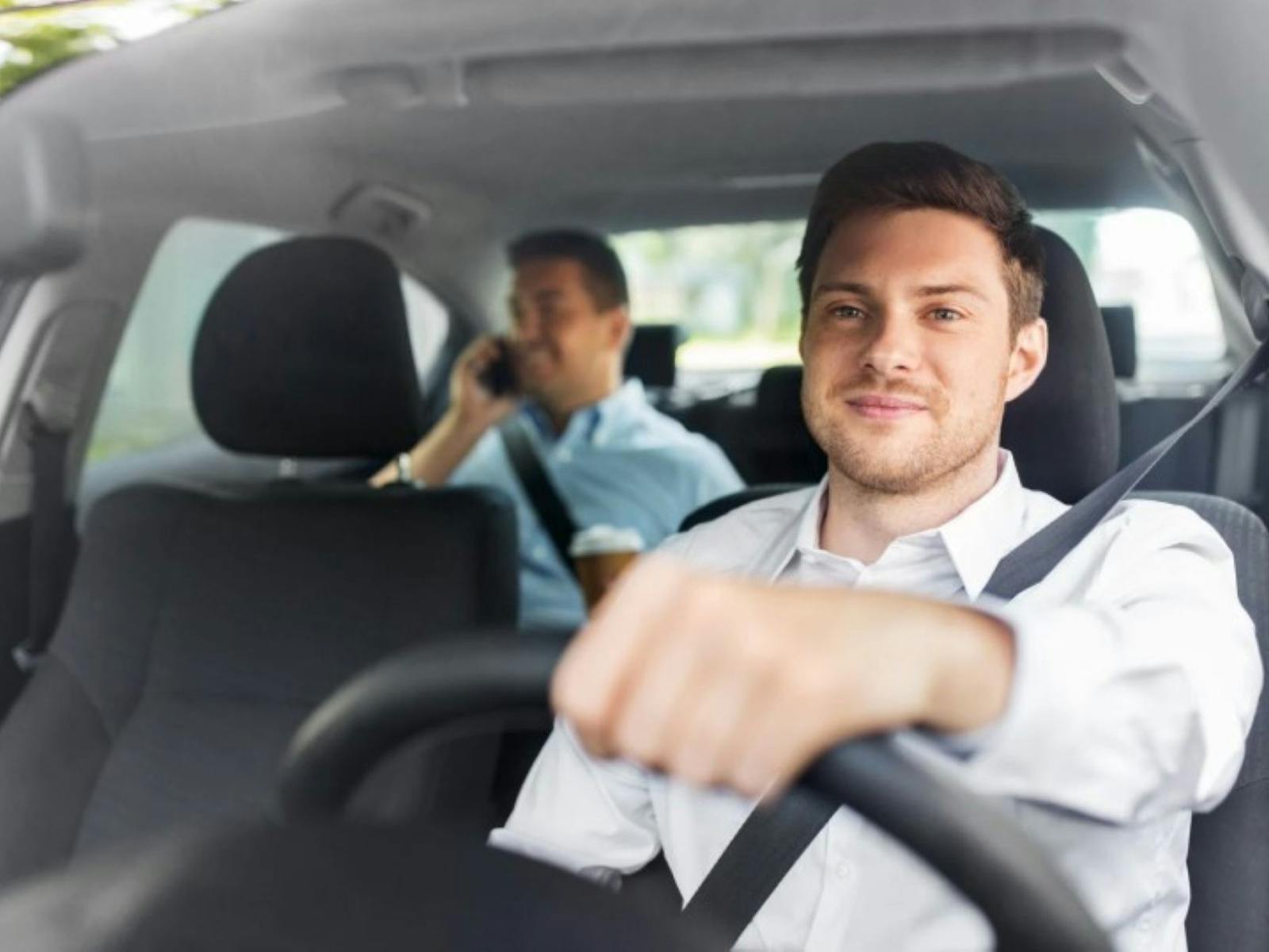 Taxi driver driving with a passenger in the back seat