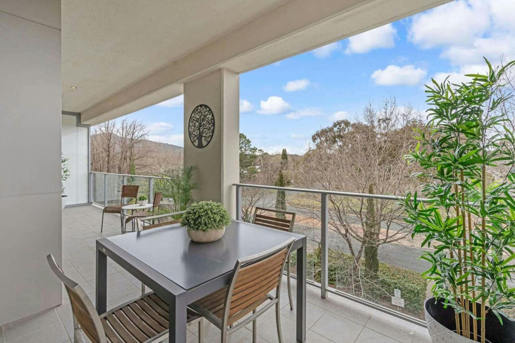 Covered balcony with outdoor dining table and leafy green views.