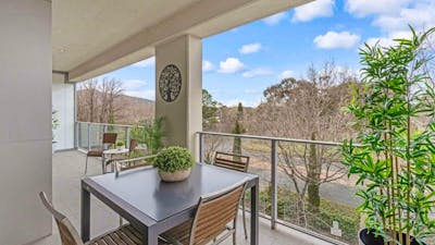 Covered balcony with outdoor dining table and leafy green views.