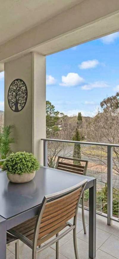 Covered balcony with outdoor dining table and leafy green views.