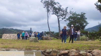 People walking on raised ground with stone wall and sign