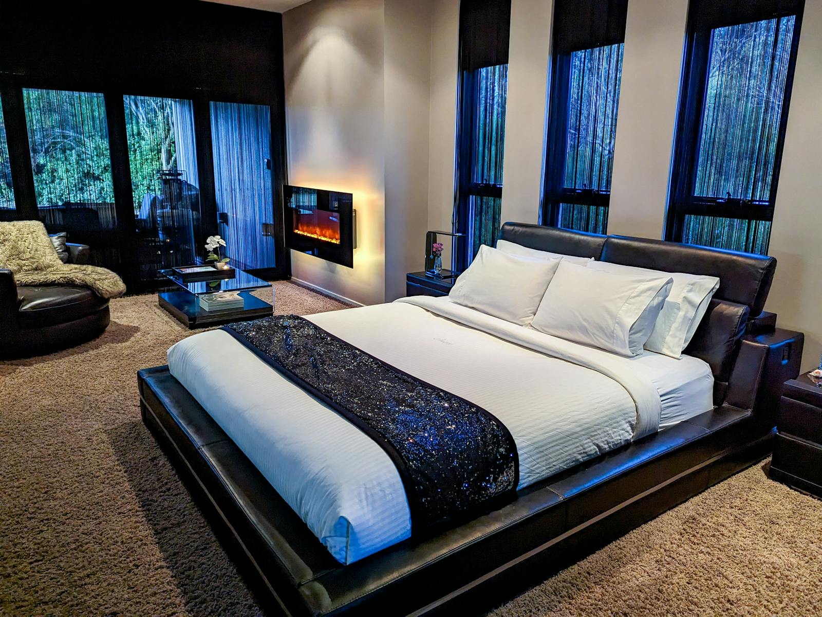 A room with a kingsize bed, fire place and comfortable chair