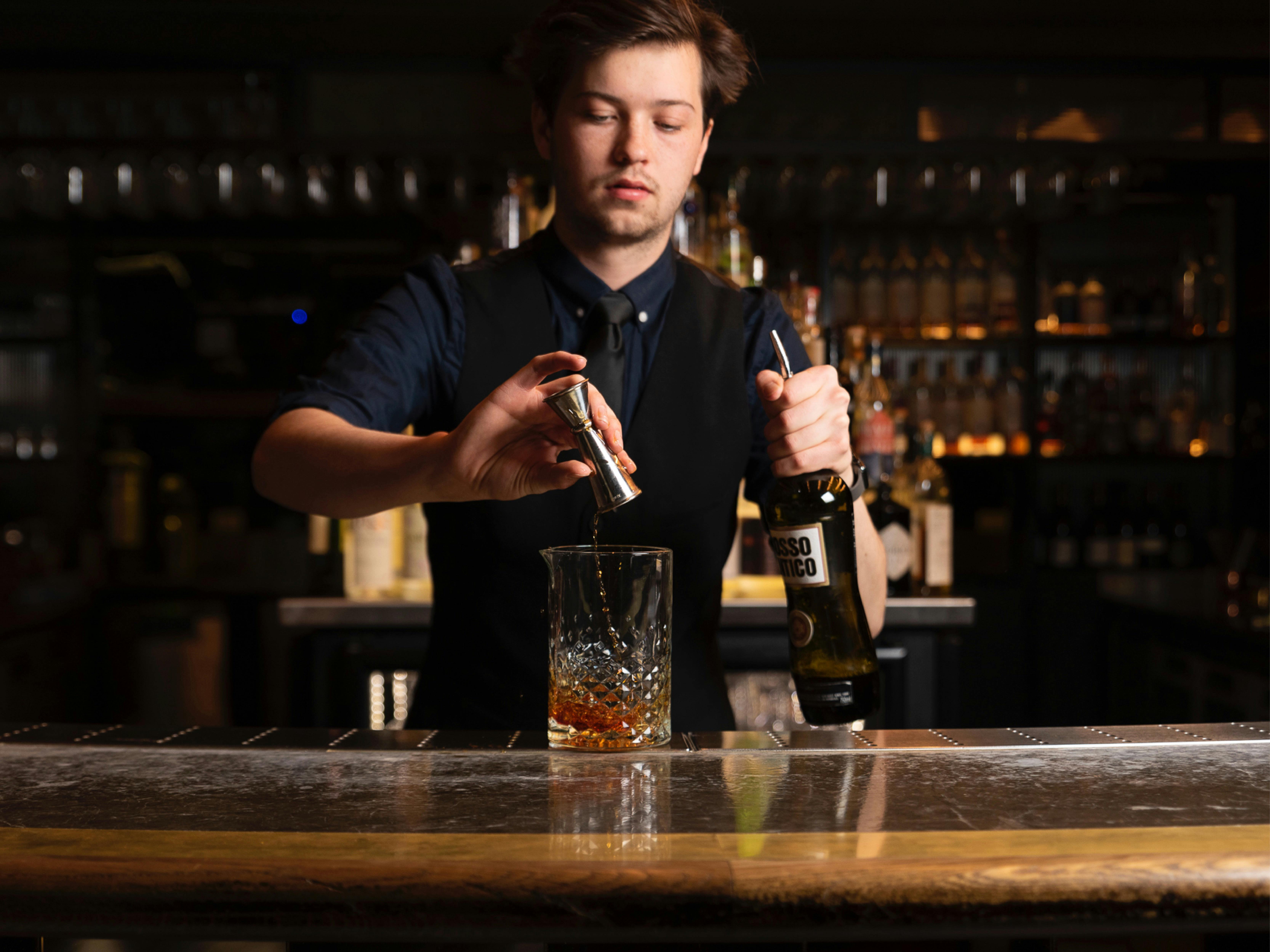 Cocktail bar and a bartender pouring a drink in a glass