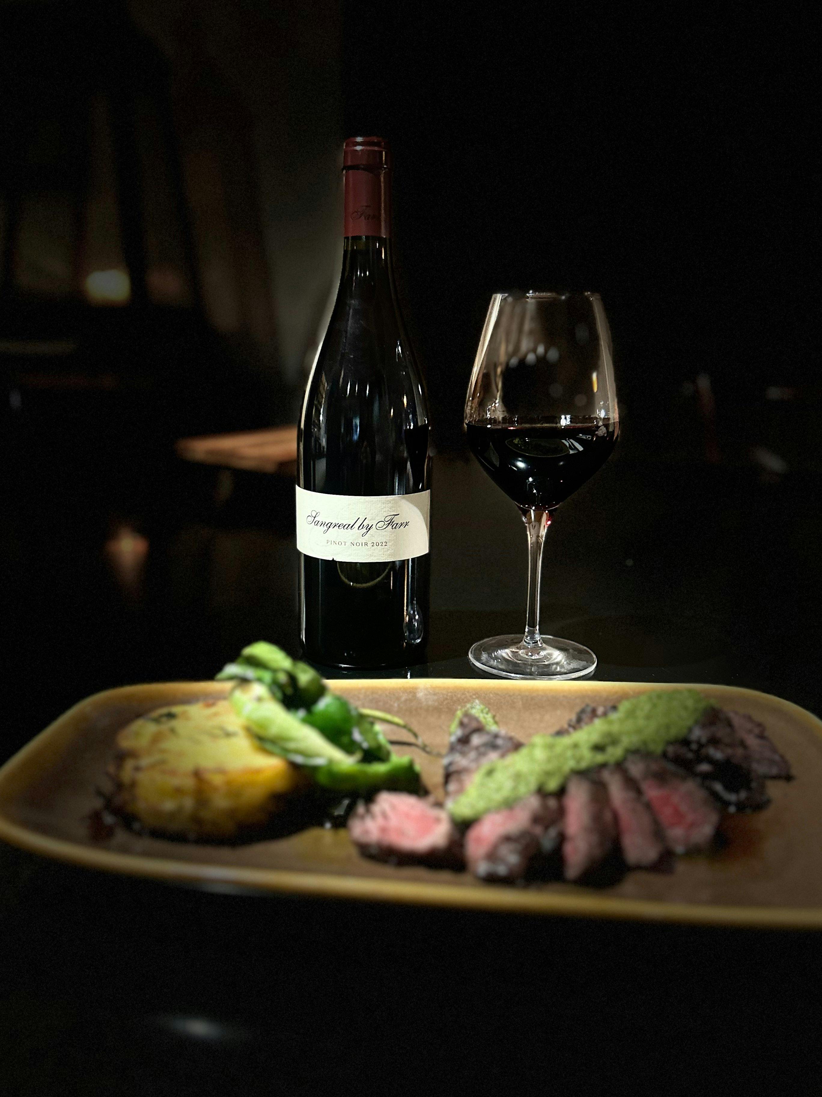 Close‑up of By Farr Pinot  beside a  steak at Feathertop Restaurant.