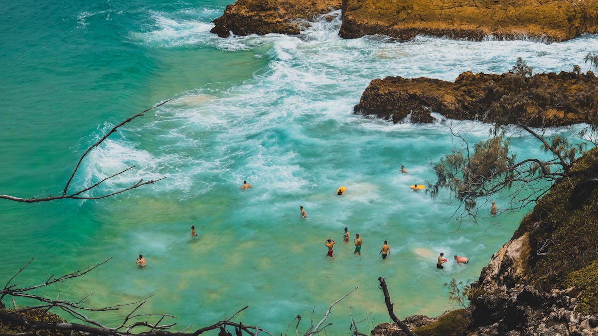 People swimming in turquoise water surrounded by cliffs and natural scenery on North Stradbroke Isla