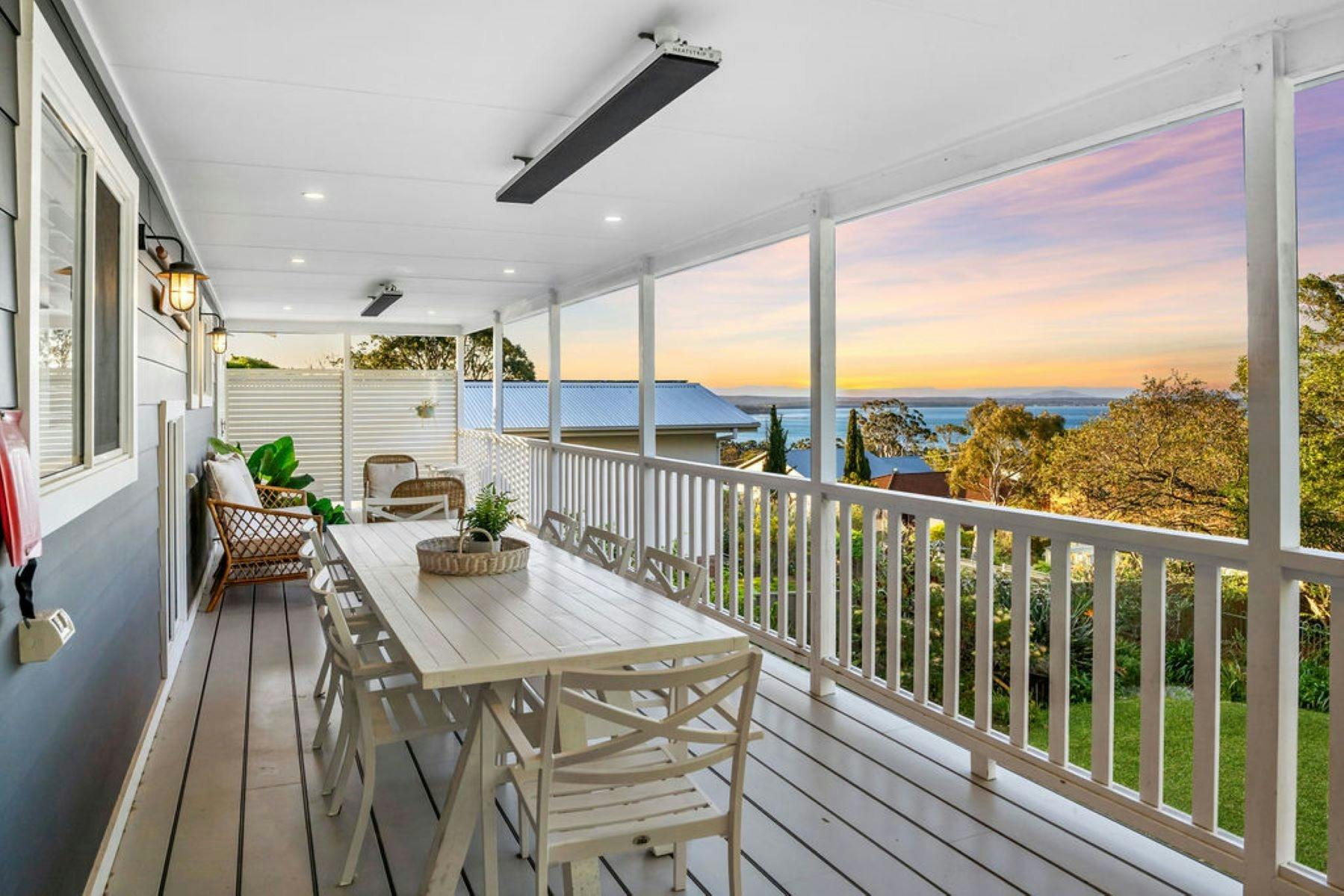 뒷쪽 데크 이미지. 야외 식사 테이블이 데크에 있습니다. 배경에 바다가 보입니다.