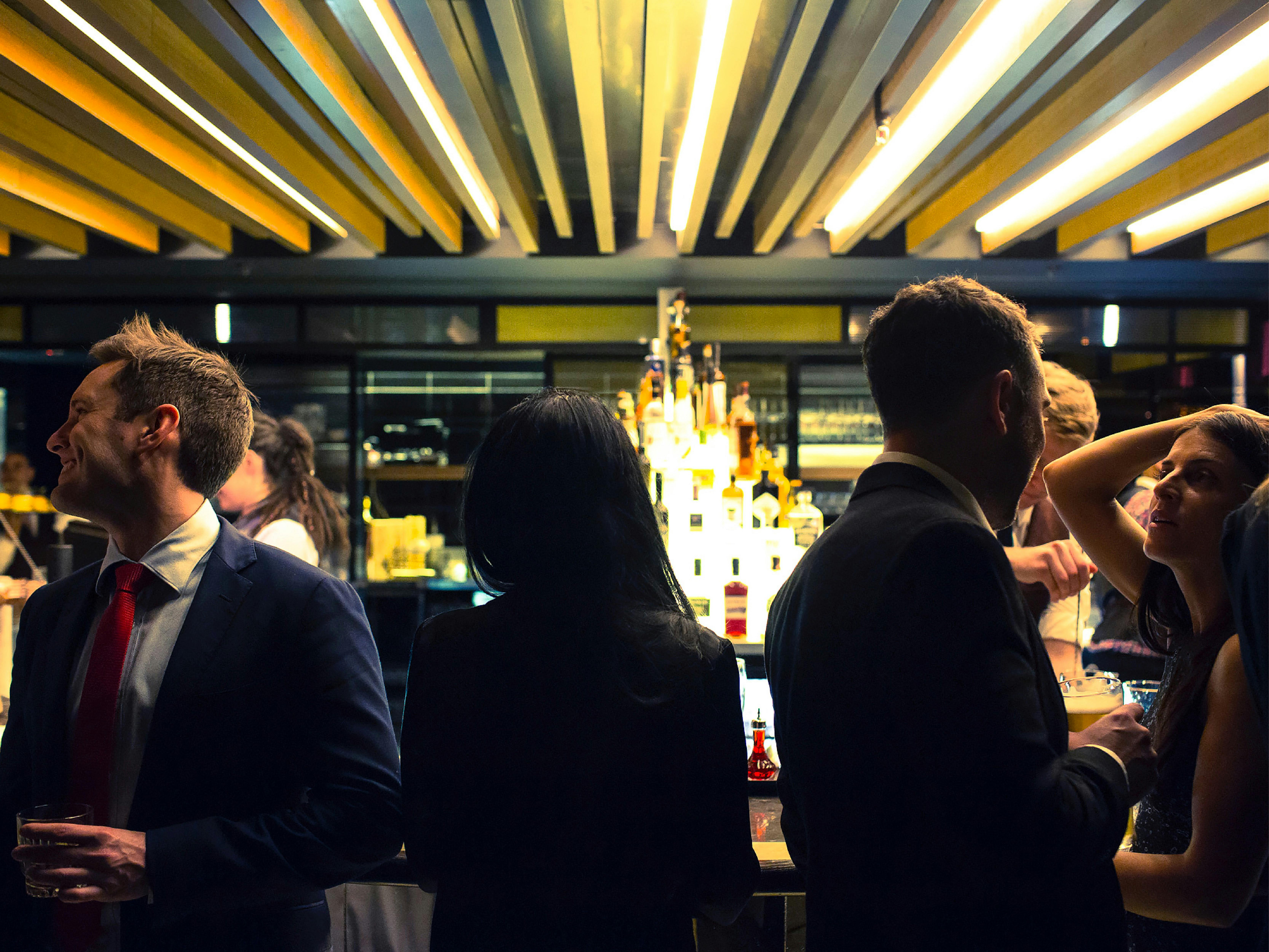 Cocktail bar and people surrounding the bar talking and laughing