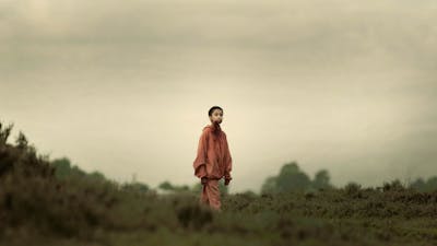 Young child with shaved head stands in isolated surrounds with blood around mouth