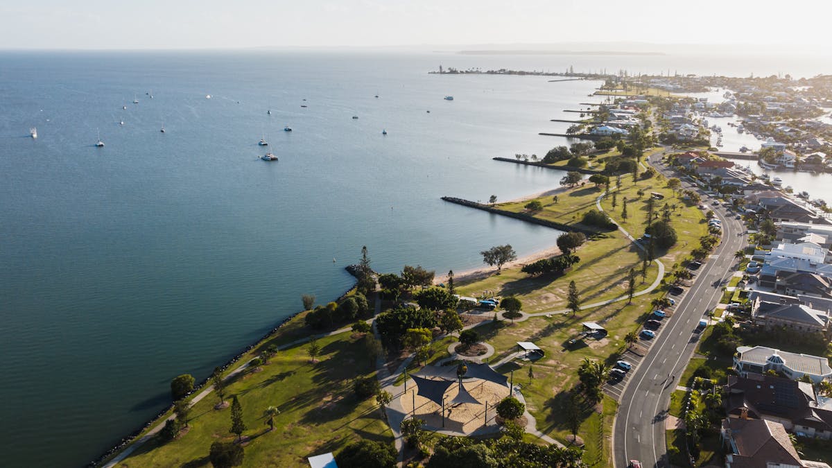 Aerial view of Raby Bay Foreshore showing parklands & boats moored along the coastline in Cleveland.