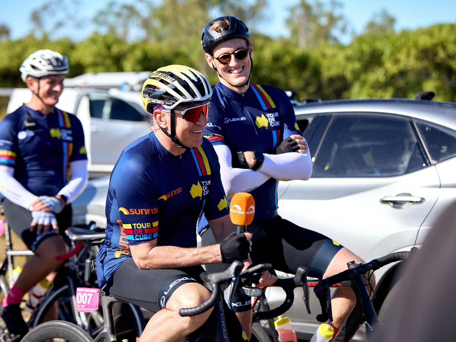 Mark Beretta and Mack Horton casually sitting on their bikes in cycle kit during Signature Tour '25