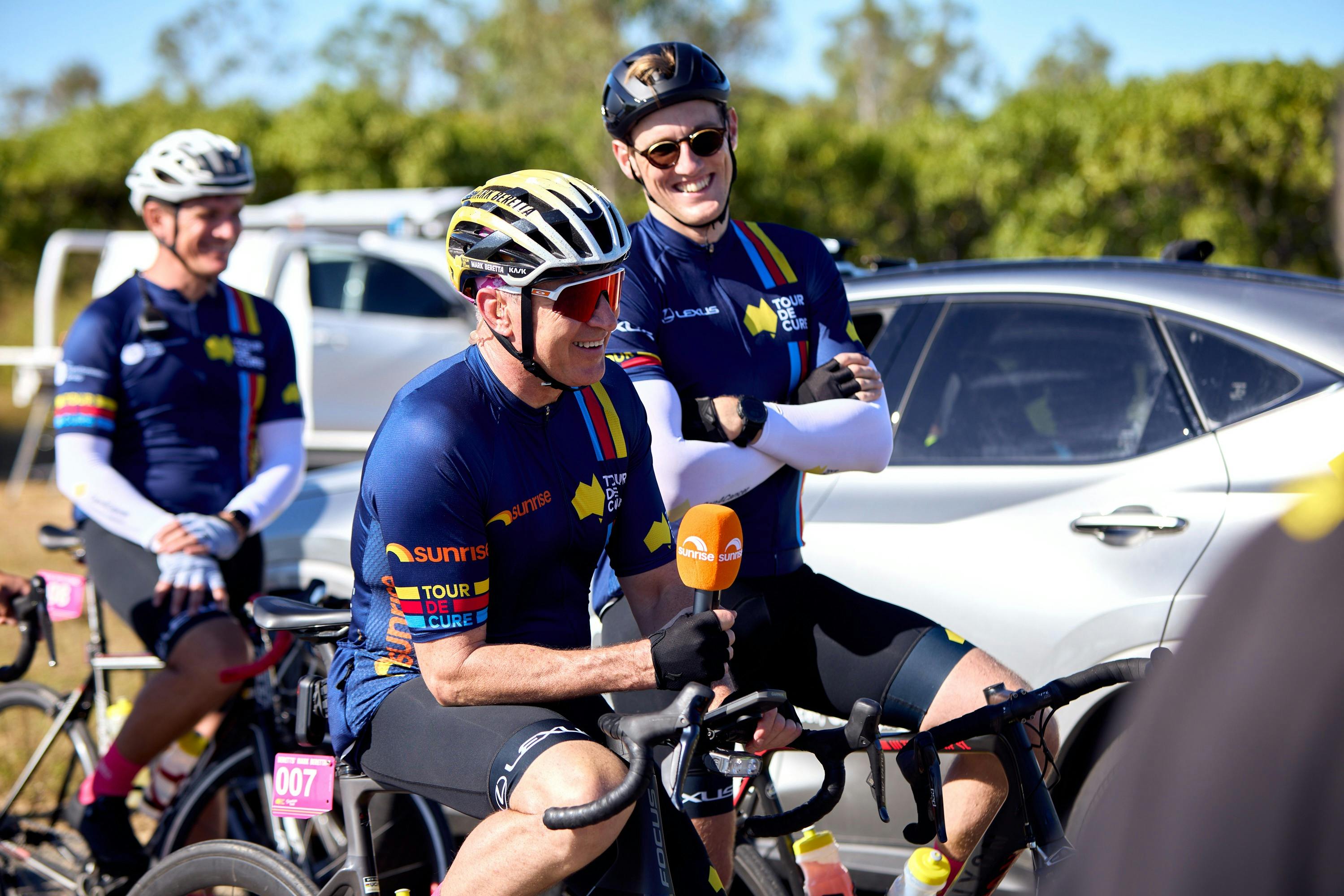 Mark Beretta and Mack Horton casually sitting on their bikes in cycle kit during Signature Tour '25