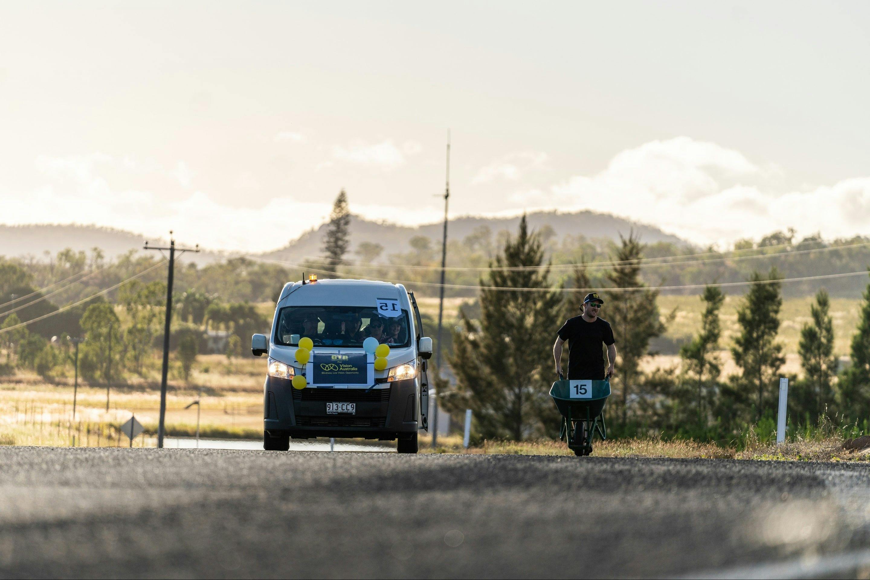 A man in a black shirt runs with a wheelbarrow along the Wheelbarrow Way in Mareeba, Far North Qld.