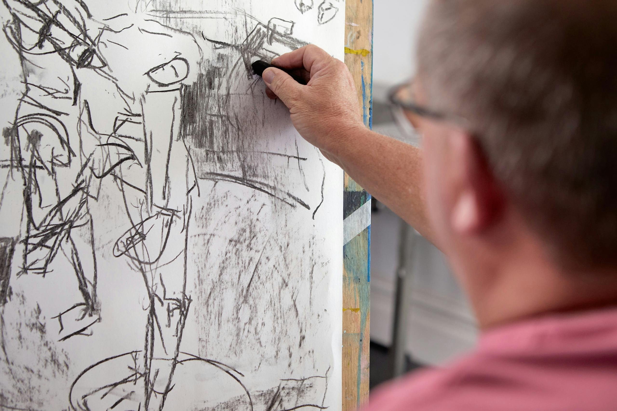 Man sketches at easle with charcoal