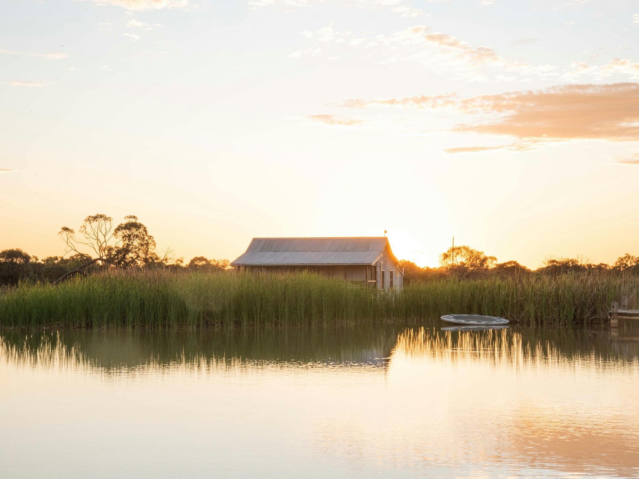 A view of a cottage adjacent to a lake at sunset A view of a cottage adjacent to a lake at sunset