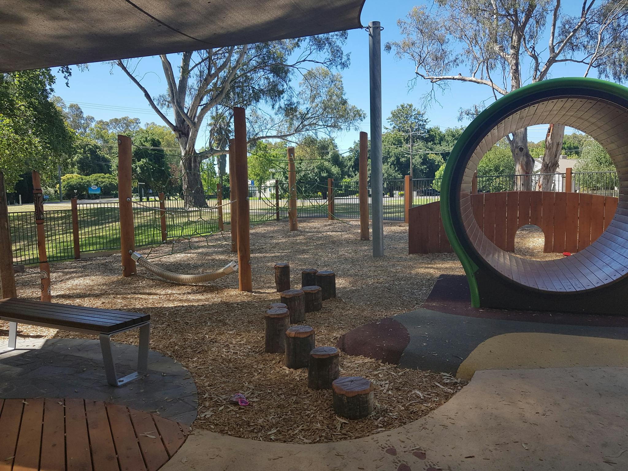 Childrens play ground, seat, stepping stones, tunnel, rope climbing structure, blue sky, grass, tree